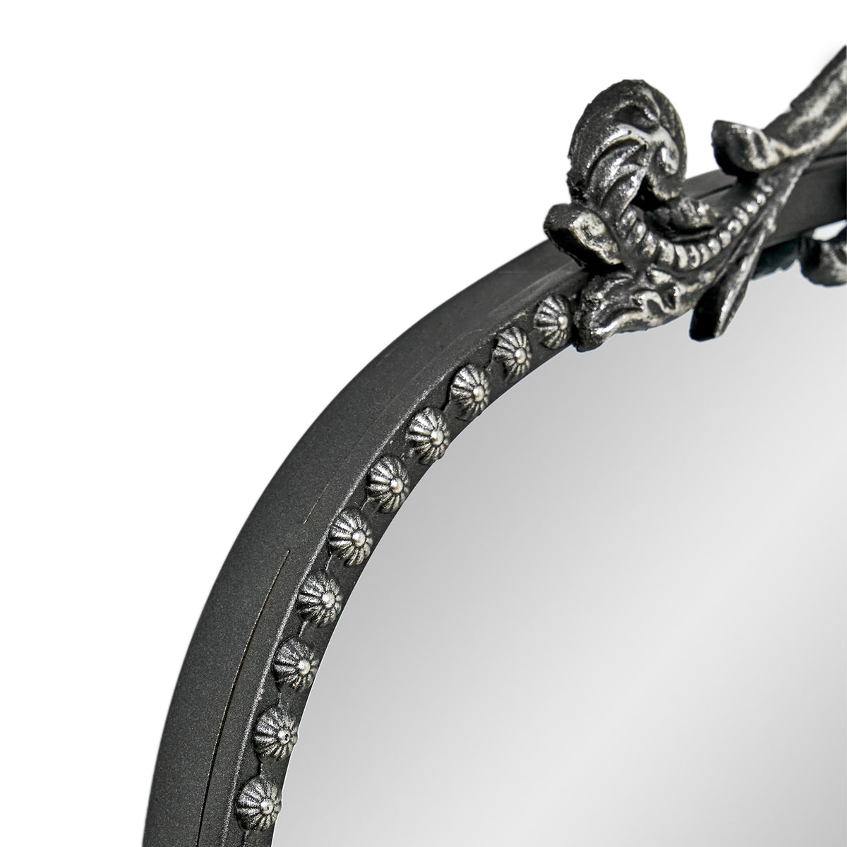 A 20 x 30 pewter arched vanity mirror with antique silver filigree crest and beaded edge, mounted vertically above a compact dresser in a bright neutral room.