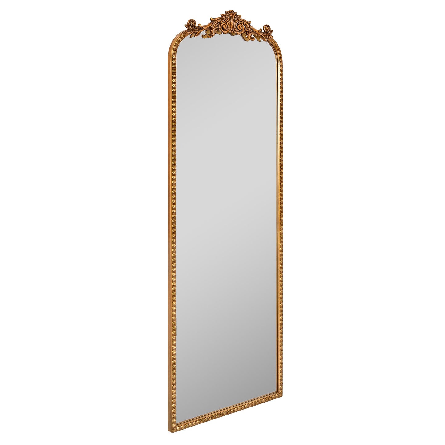 A slim 22 x 64 antique gold arched full body mirror with ornate filigree crest and floral-bead border, leaning beside a dresser and closet in a warm bedroom.