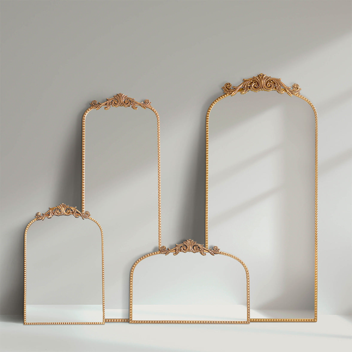 A wide 24 x 34 antique gold arched mirror with ornate filigree crest and beaded frame, styled horizontally above a mantel with candles, florals and warm room decor.