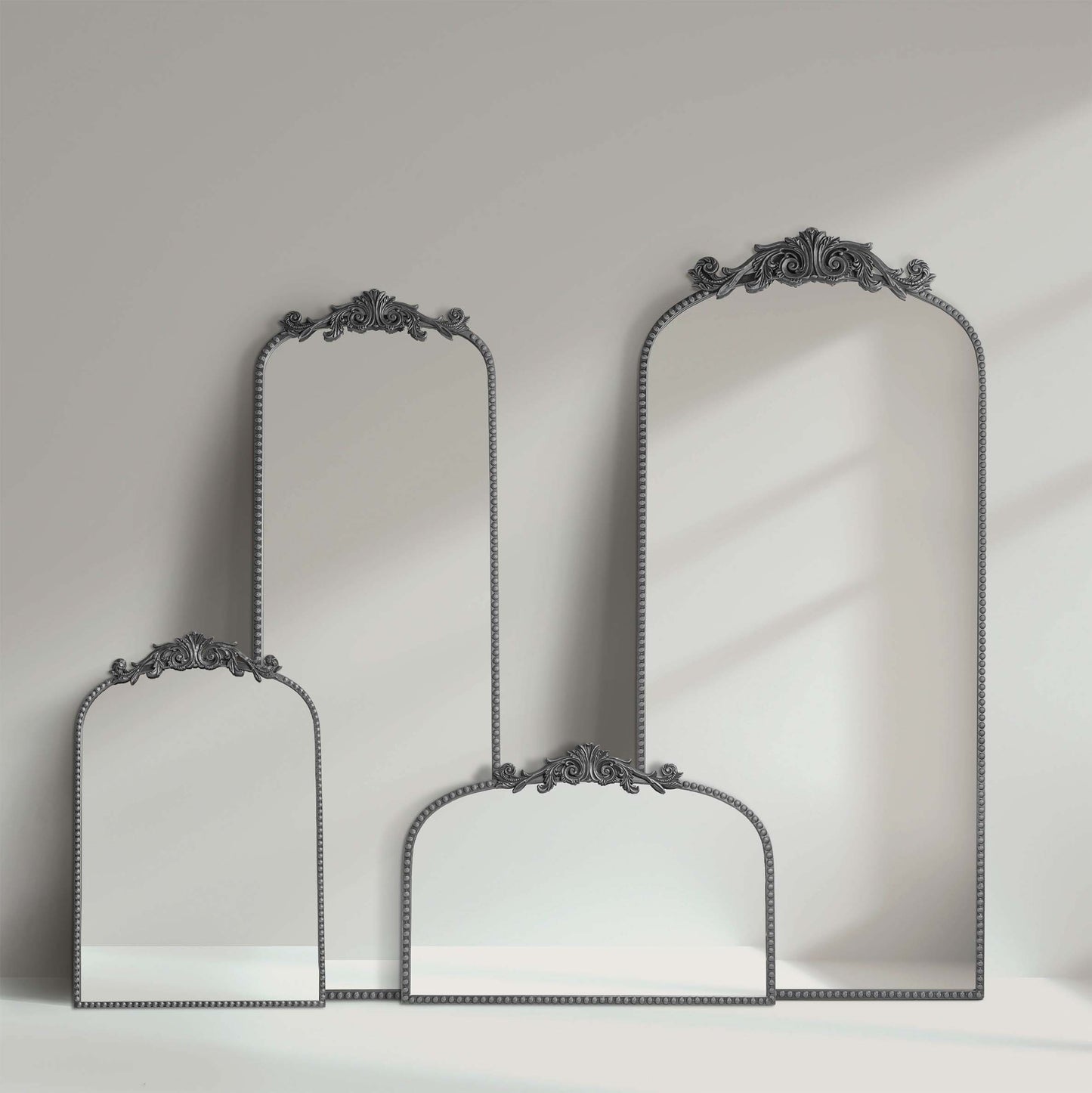A 24 x 34 pewter arched wall mirror with antique silver filigree crest and beaded trim, displayed horizontally above a vanity or console in a polished neutral interior.